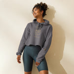 Woman wearing a gray hoodie with a lion graphic and teal shorts against a beige background