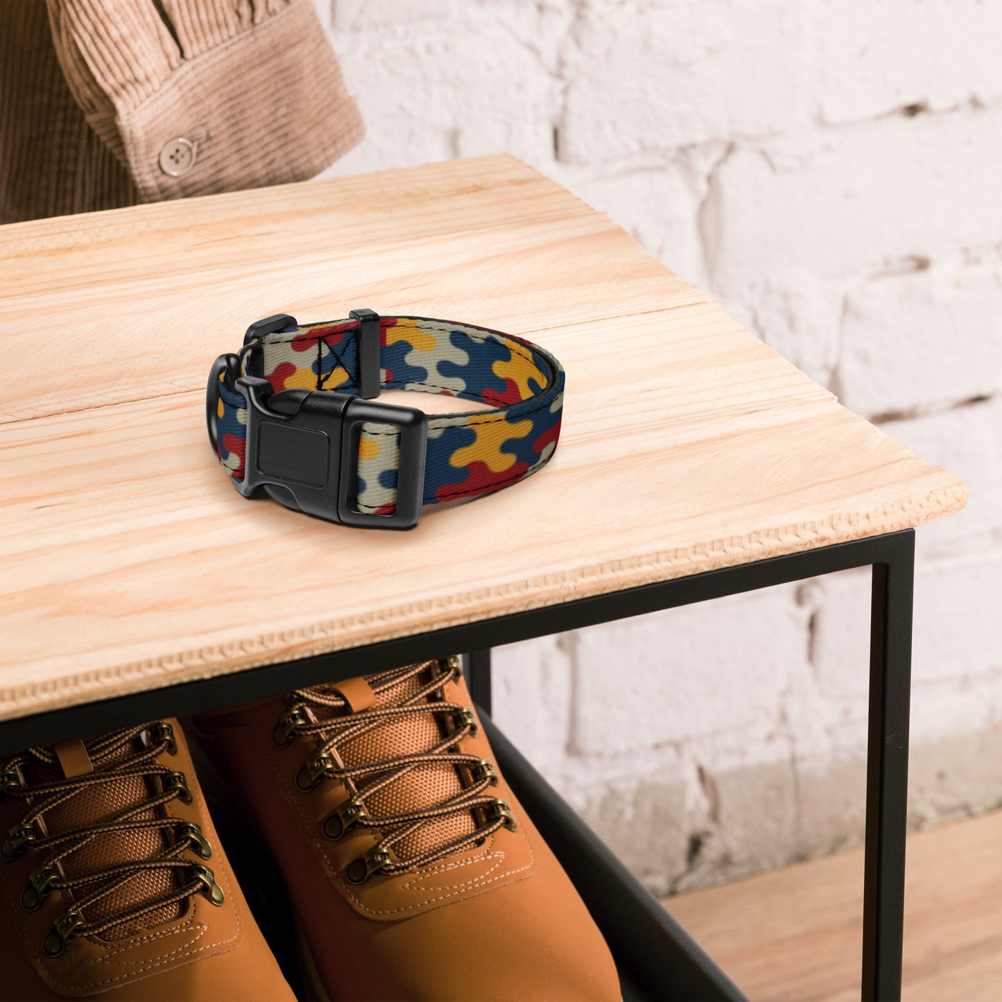 Colorful dog collar on a wooden table with brown boots underneath.